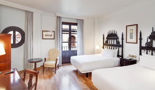 um quarto de hotel com duas camas e uma secretária em Sercotel Palacio de los Gamboa em Granada