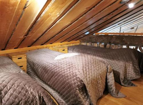 two beds in a attic room with wooden ceilings at Rukanhelmi jr. in Ruka