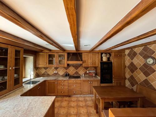 a large kitchen with wooden cabinets and a table at Casa do Caseiro Muxía in Muxia