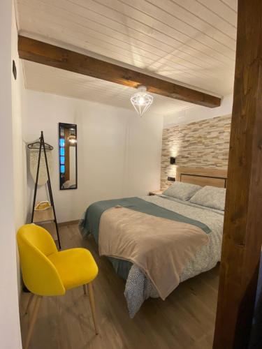 - une chambre avec un lit et une chaise jaune dans l'établissement Apartamentos Rurales Calleabajo - 3 Estrellas, à Hervás