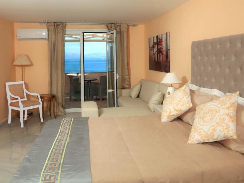 a bedroom with a large bed with a view of the ocean at Cavomarina Beach- Adults Only in Kavos