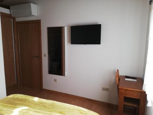 a bedroom with a tv on a white wall at Quintinha dos Emigrantes in Cujó