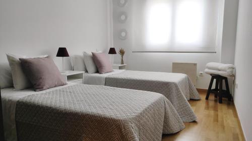 two beds in a white room with a window at En Ribeira para 4 céntrico con parking in Ribeira