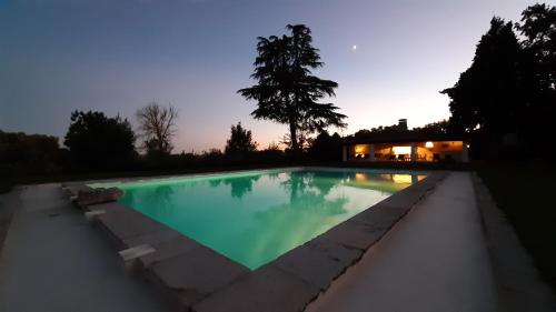 a swimming pool at dusk with a house in the background at Casas da Piedade in Azinhaga