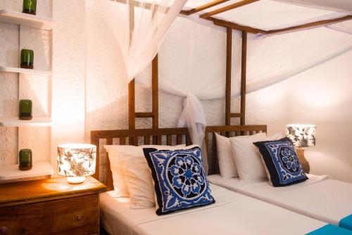 a bedroom with two beds with blue and white pillows at Villa Lala in Kiwengwa