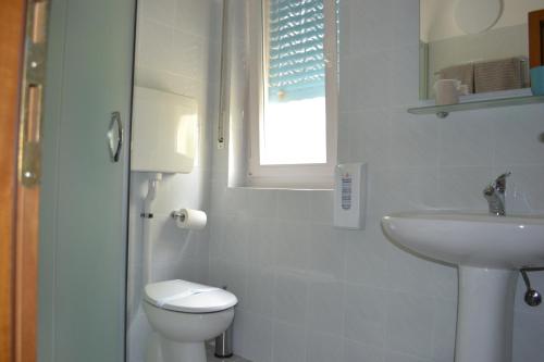 a white bathroom with a toilet and a sink at GARNI ANNA in Besenello