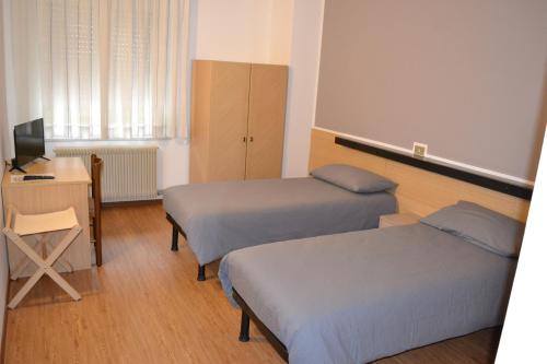 a room with two beds and a desk and a television at GARNI ANNA in Besenello