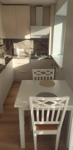 cocina con mesa blanca y 2 sillas en Butas miesto centre/ Apartment in the city center, en Šiauliai
