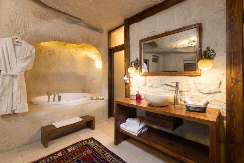 Un baño con lavabo, bañera y espejo. en Doors Of Cappadocia Special Cave Hotel, en Göreme