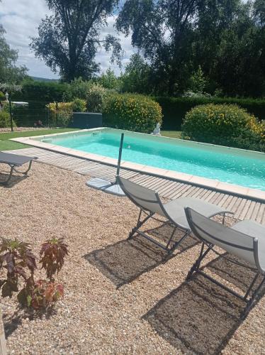 - une piscine avec deux chaises en face dans l'établissement Maison 3 étoiles avec piscine et jacuzzi extérieur près de Sarlat, à Saint-Vincent-le-Paluel