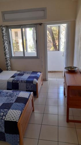 um quarto com duas camas e uma secretária e duas janelas em Adarissa House em Rabat