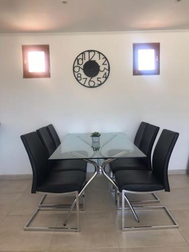 a glass table with chairs and a clock on a wall at Villa mit großartigem Panoramablick auf das Meer und direkt am Pool in La Croix-Valmer