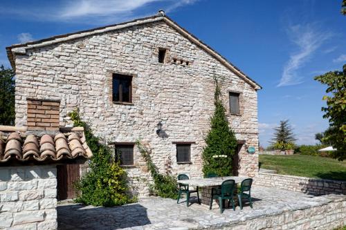 a stone building with a table and chairs in front of it at Riserva Privata San Settimio in Arcevia