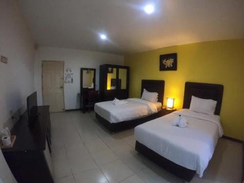a hotel room with two beds and a television at Phusuay Park View Hotel in Chaiyaphum