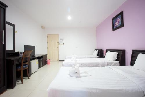 a hotel room with three beds and a desk at Phusuay Park View Hotel in Chaiyaphum