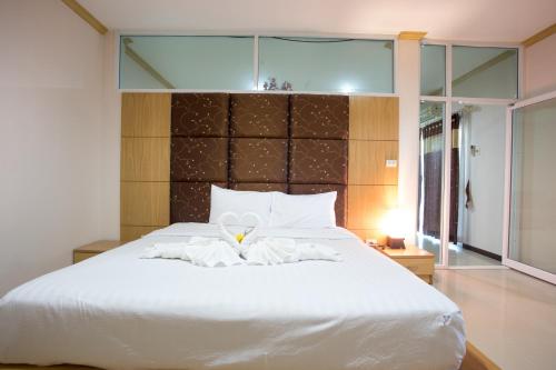 a bedroom with a white bed and a large window at Phusuay Park View Hotel in Chaiyaphum