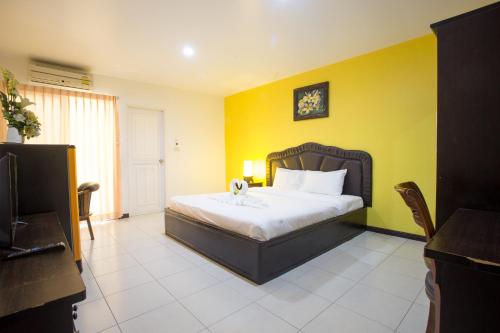 a bedroom with a bed and a yellow wall at Phusuay Park View Hotel in Chaiyaphum