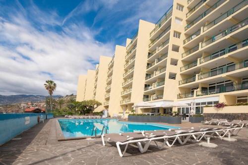 a hotel swimming pool with lounge chairs and a building at Tranquil Beachside Stay - Atlantic Gardens Beach in Funchal