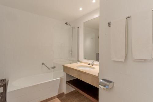 a white bathroom with a sink and a shower at Tranquil Beachside Stay - Atlantic Gardens Beach in Funchal