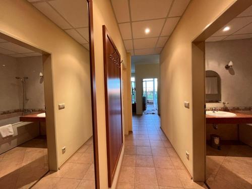a hallway of a bathroom with two sinks and a mirror at "Красавиците тъмнокоси" Sunset Resort Pomorie in Pomorie