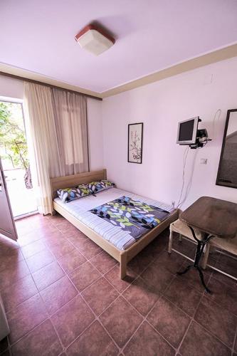 a bedroom with a bed and a desk and a tv at Vila Mila in Petrovac na Moru