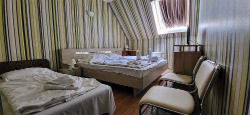 a bedroom with two beds and a chair and a window at Hotel Korona in Siófok