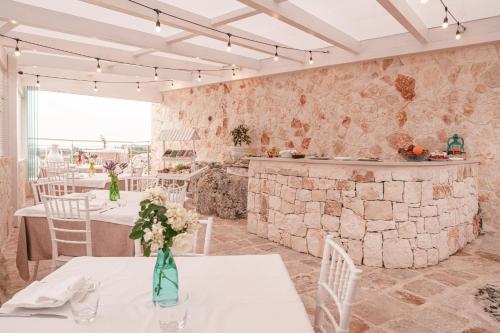 a restaurant with white tables and chairs and a stone wall at La Terrazza Sulla Rupe Relais in Ostuni