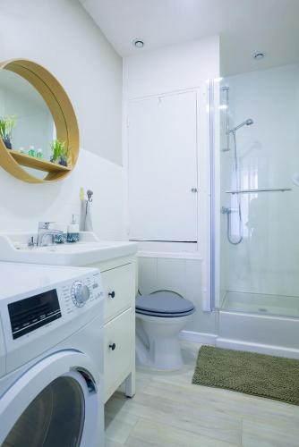 une salle de bain blanche avec une machine à laver à l'intérieur dans l'établissement L'HELLENID - Logement Spacieux Proche Cour d'appel Riom, à Riom