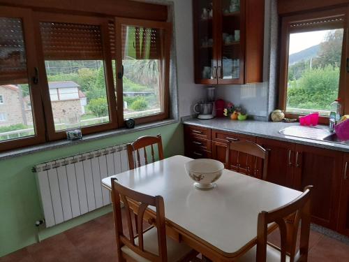 een keuken met een tafel, stoelen en ramen bij Casa Herbellas in Cedeira