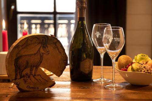 a bottle of wine and two wine glasses on a table at Maison Cly in Chamois