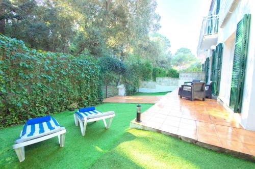 a yard with two blue and white chairs on the grass at Casa Playa by Sonne Villas in Ferreries