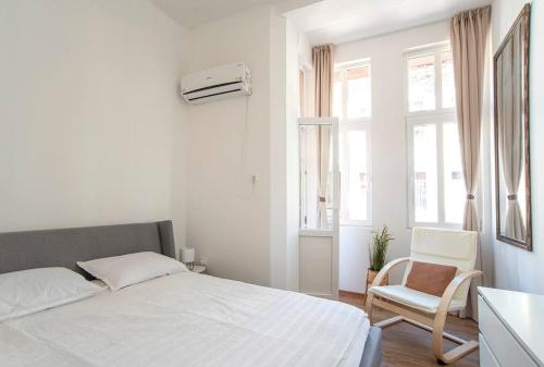 a white bedroom with a bed and a chair at Supreme Luxury Top Central 1 Bedroom Apartment in Sofia