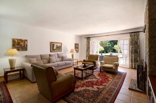 Una sala de estar con un sofá y sillas y una mesa. en Casa Alcantarilha, en Pêra