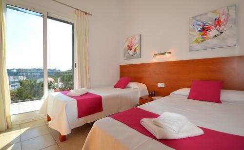 Una habitación de hotel con dos camas y una gran ventana. en Villa Azucena by Sonne Villas, en Cala Galdana