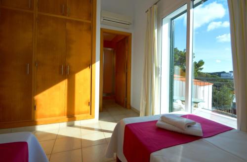 a bedroom with a bed and a large window at Villa Azucena by Sonne Villas in Cala Galdana