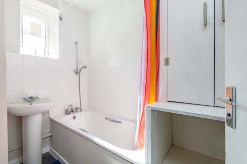y baño blanco con lavabo, bañera y ducha. en One bedroom apartment en Londres