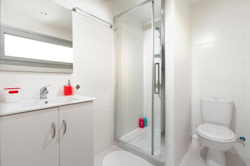 a white bathroom with a shower and a toilet at Myrtiana Apartments in Nicosia