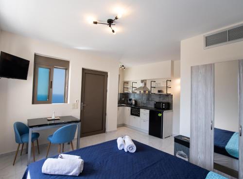 a bedroom with a blue bed and a desk and a kitchen at MELIKIRON LUXURY APARTMENTS in Agios Nikitas