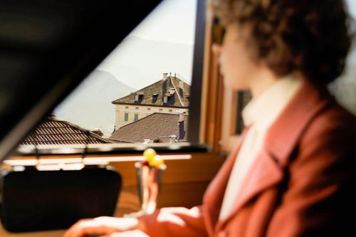 a woman sitting in front of a window looking at a building at Weisses Rössl in Caldaro
