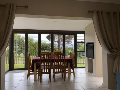ein Esszimmer mit Tisch und Stühlen und einem Fernseher in der Unterkunft Gable Cottages No.4 Clarens in Clarens