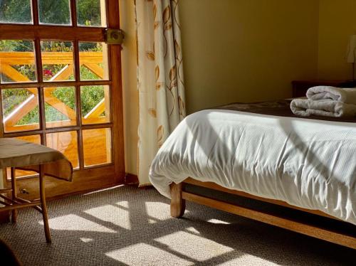 a bedroom with a bed next to a window at Apu Lodge in Ollantaytambo