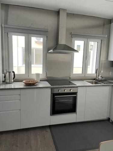 uma cozinha com armários brancos e um forno com placa de fogão em Casa Mar Azul em Nazaré