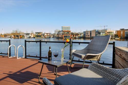 a patio with two chairs and a table with a bottle of wine at Houseboat studio with canalview and free bikes in Amsterdam