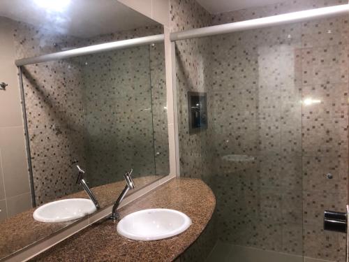 baño con 2 lavabos y ducha de cristal en Victory Business Flat, en João Pessoa