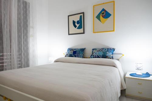 sypialnia z białym łóżkiem i 2 zdjęciami na ścianie w obiekcie Casa Belvedere riviera Taormina w mieście SantʼAlessio Siculo