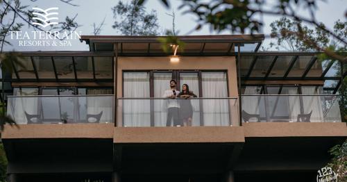 a couple standing on a balcony of a house at Tea Terrain Resorts & Spa in Vagamon