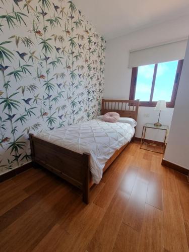 ein Schlafzimmer mit einem Bett mit tropischer Tapete in der Unterkunft Apartamento La Villa in Valverde