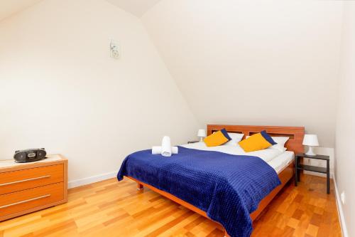 a bedroom with a bed with a blue blanket and yellow pillows at Apartment Butorowy Residence by Renters Prestige in Kościelisko