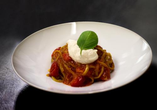 a white plate with pasta with a green leaf on it at Maison Cly in Chamois