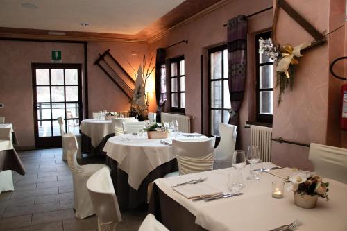 a restaurant with white tables and white chairs and windows at Maison Cly in Chamois